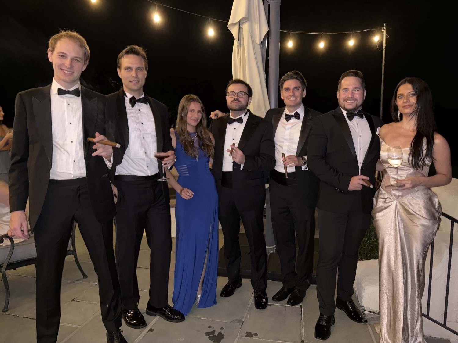 Guests in black tie on the terrace at night.